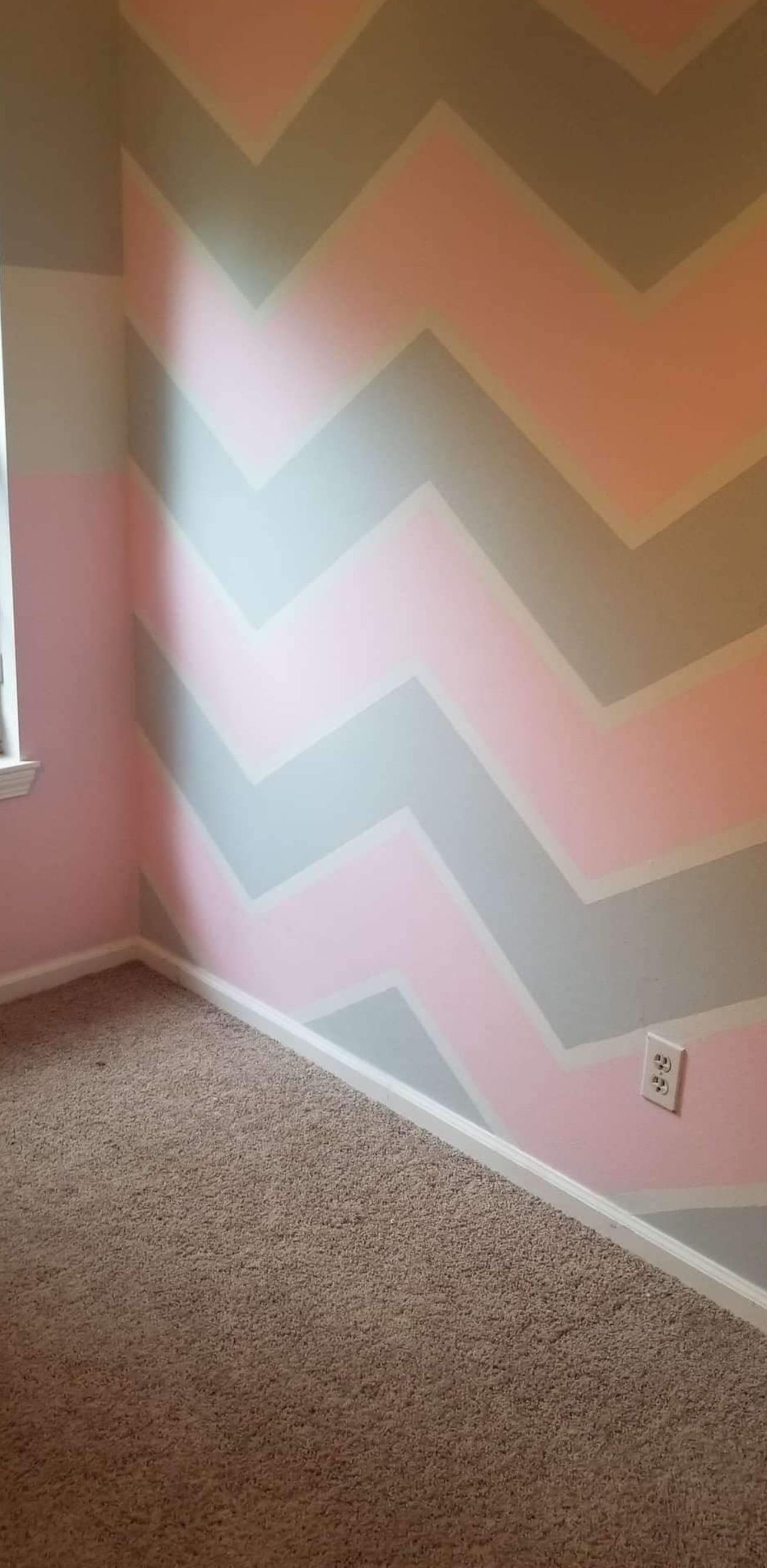 A room with a chevron pattern on the walls and a window.