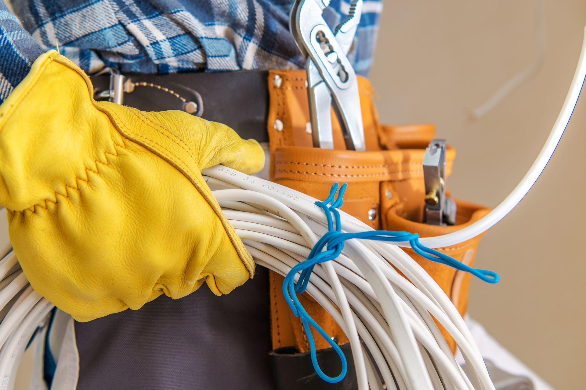 Gloved hand holding a coiled white electrical cable.