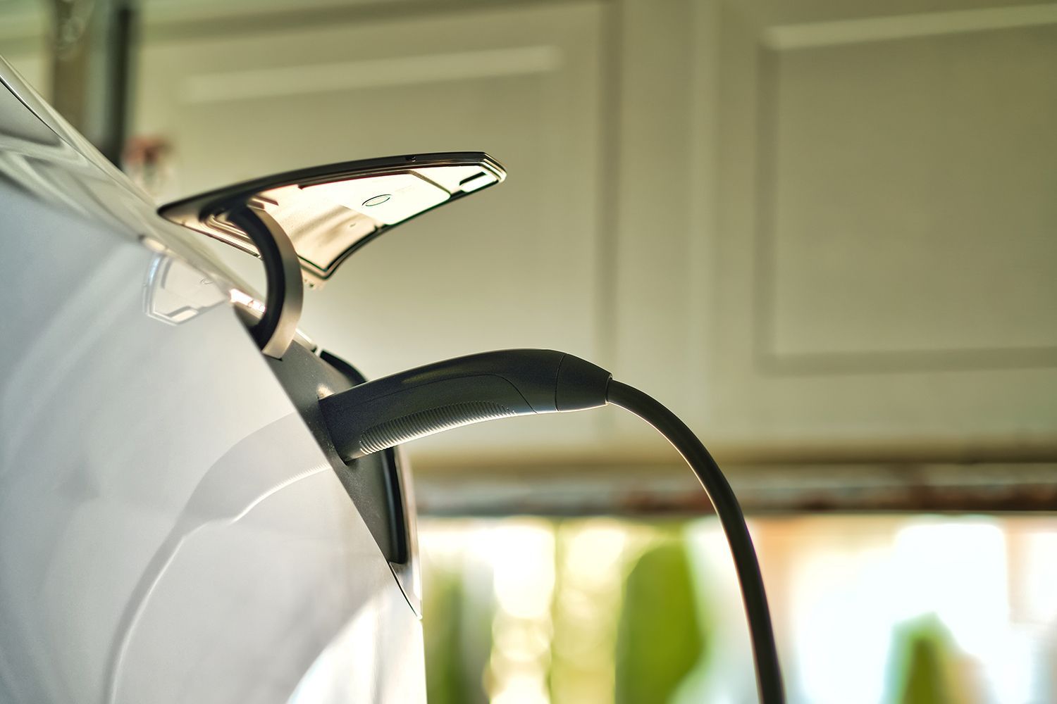 An electric car is plugged in and charging inside a garage.