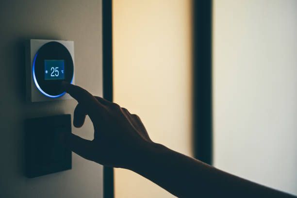 A person is pressing a button on a thermostat.