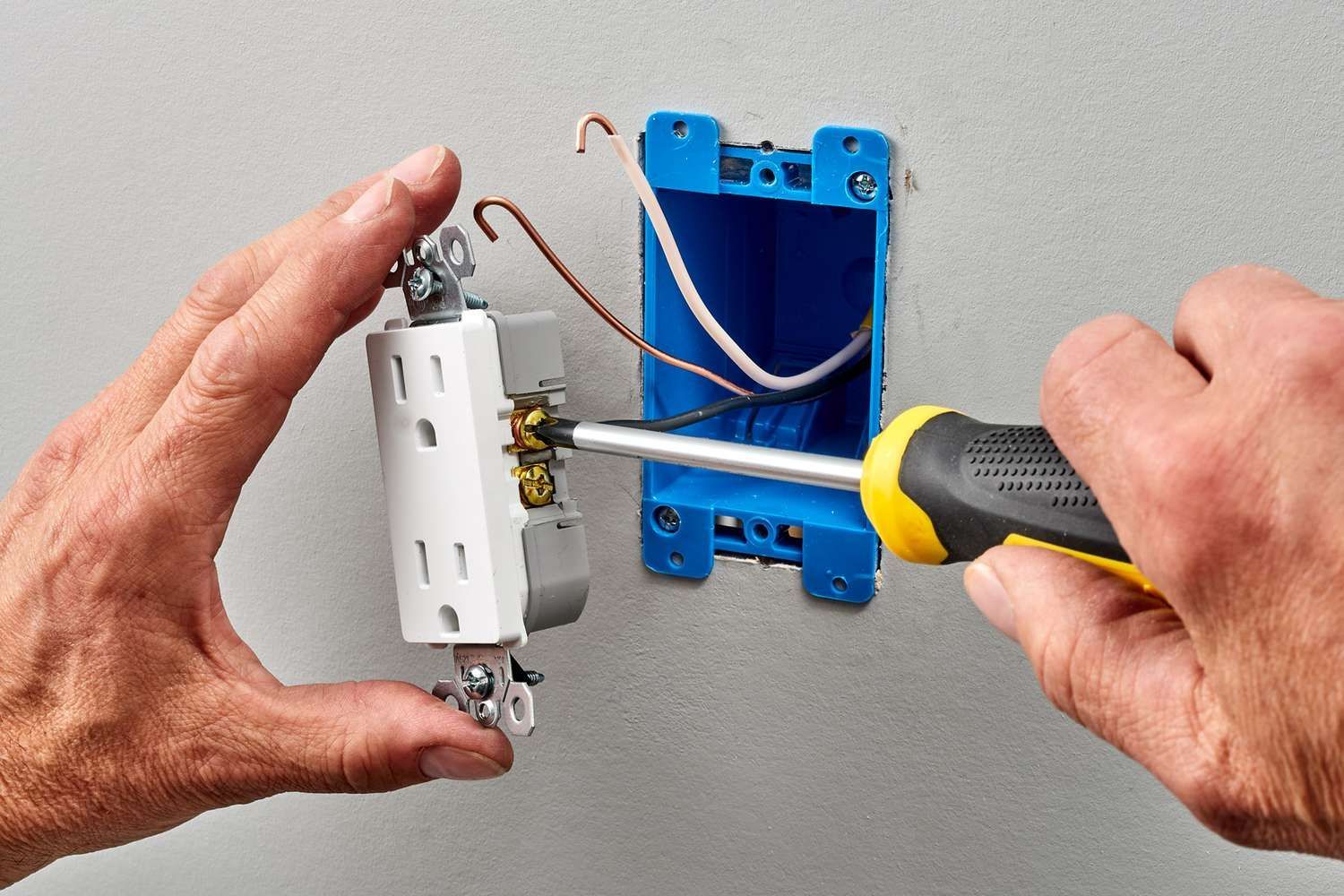 A person is plugging a cord into an electrical outlet.