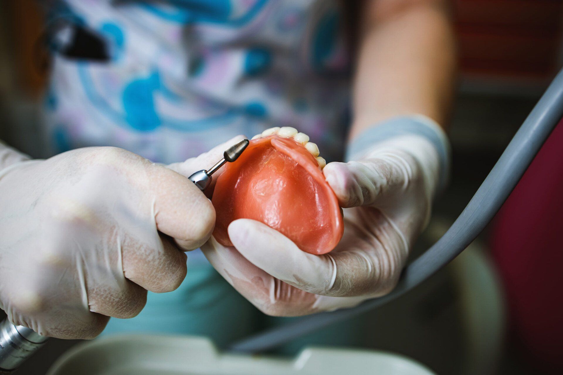 Technician shaping a prosthesis tooth with a tool | Ringwood, VIC | Abstract Arch Denture Clinic