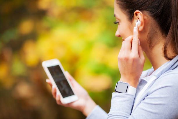 A woman is listening to music on her phone while wearing ear buds.