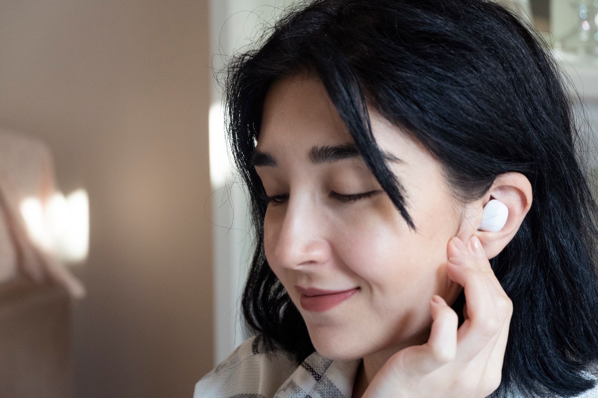 A woman is wearing a pair of white ear buds.