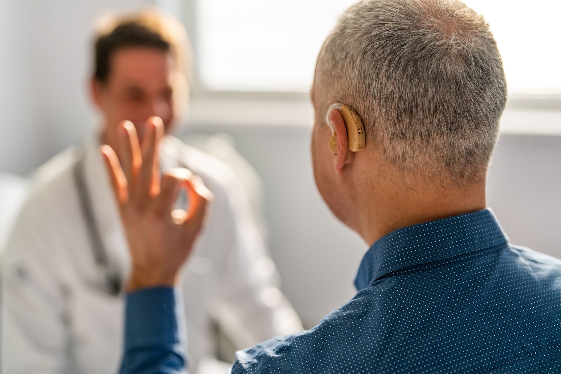 A man with a hearing aid is talking to a doctor.