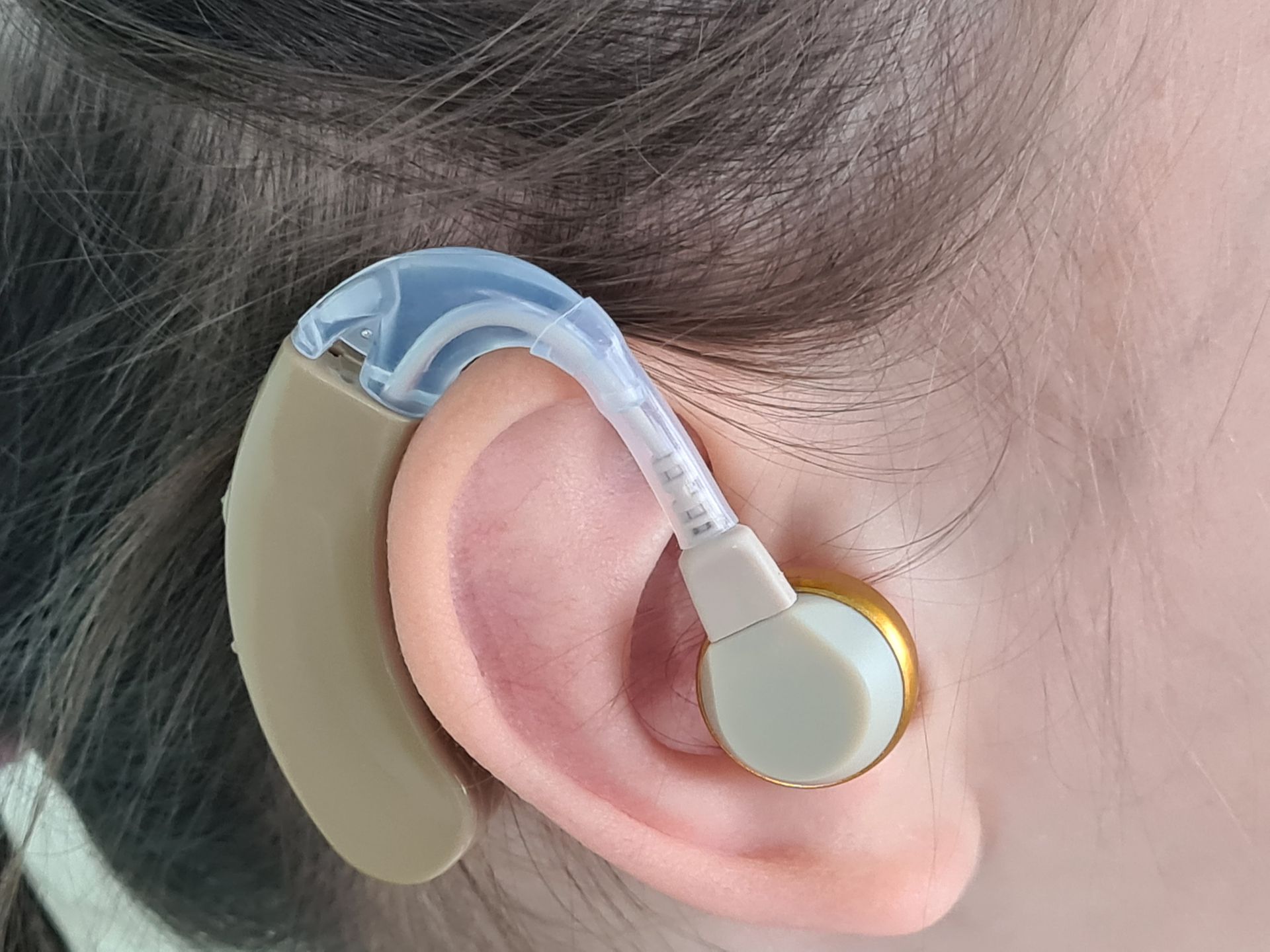 A woman is wearing a hearing aid in her left ear.