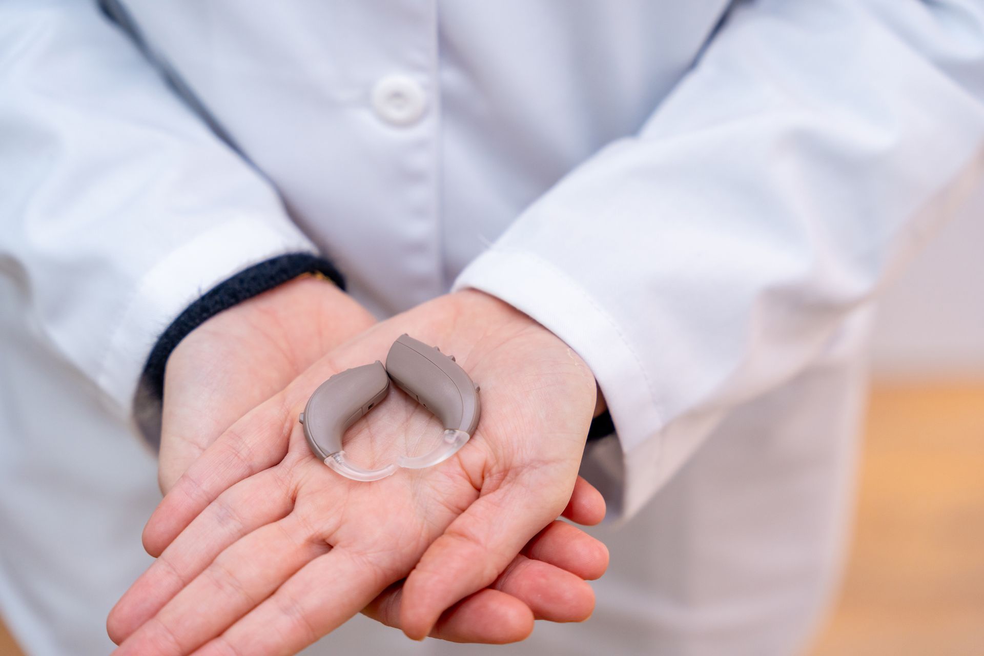 A person is holding a hearing aid in their hands.