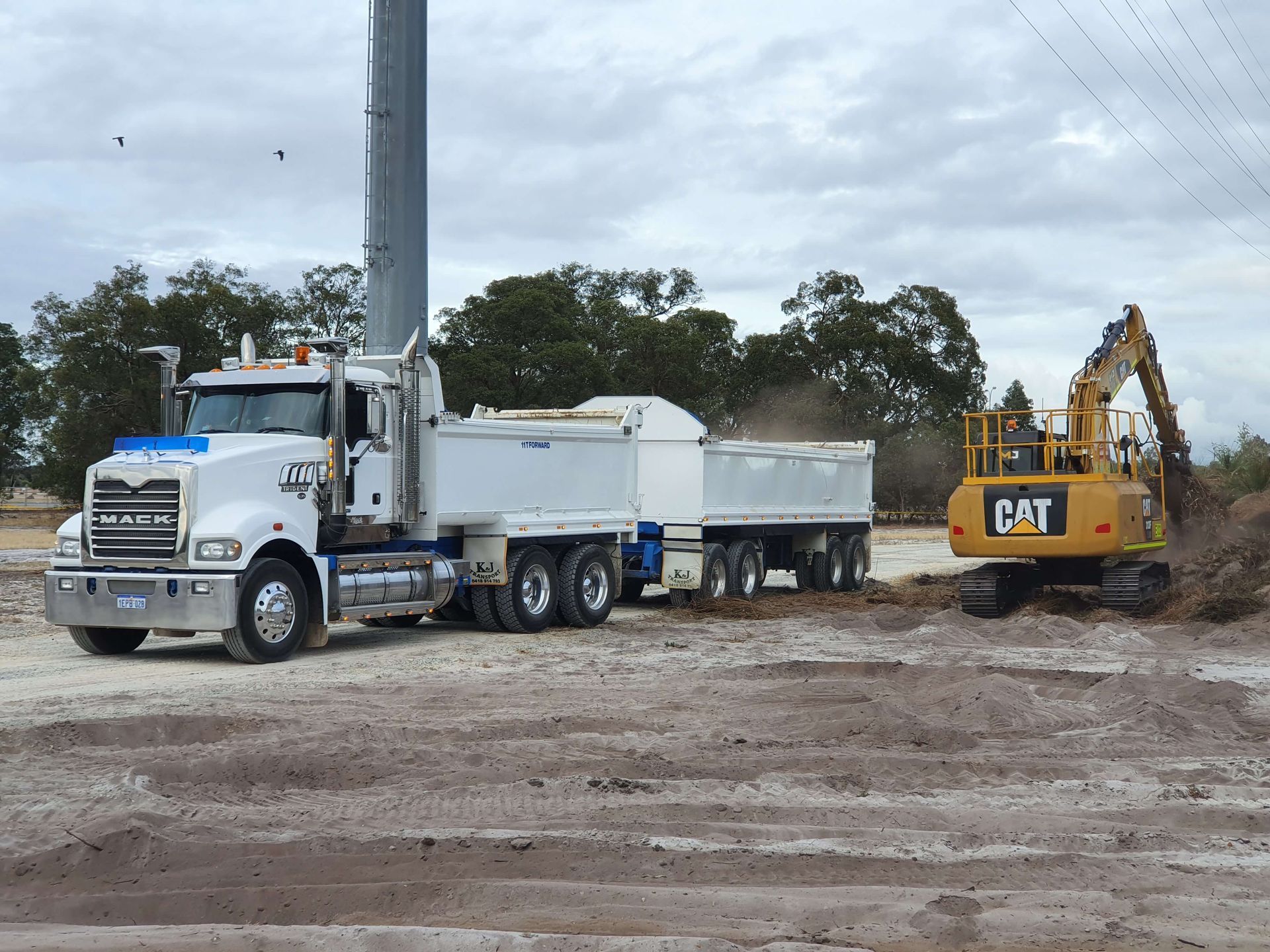 A dump truck is being towed by a cat excavator