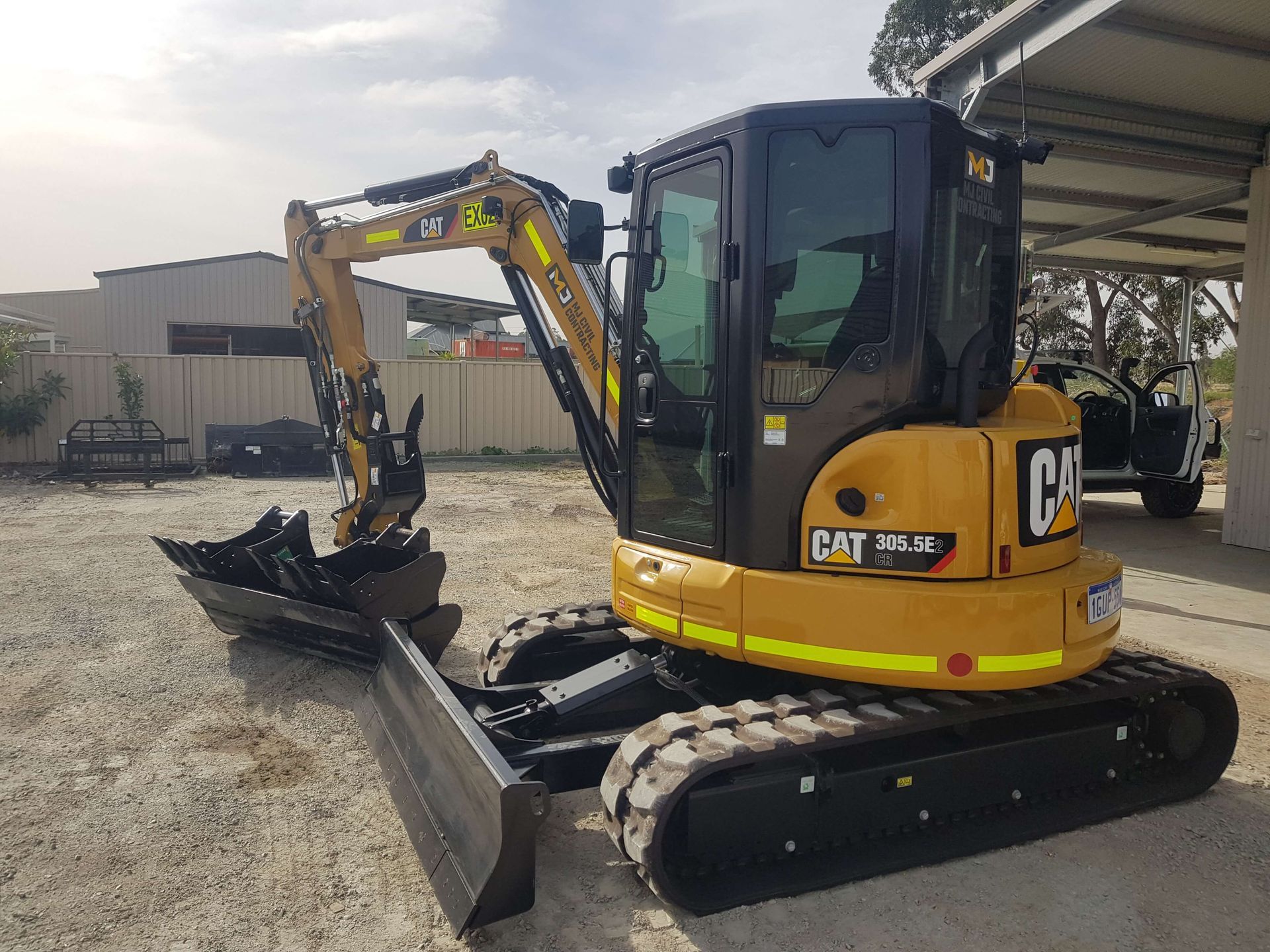 A small yellow and black excavator is parked in a parking lot.
