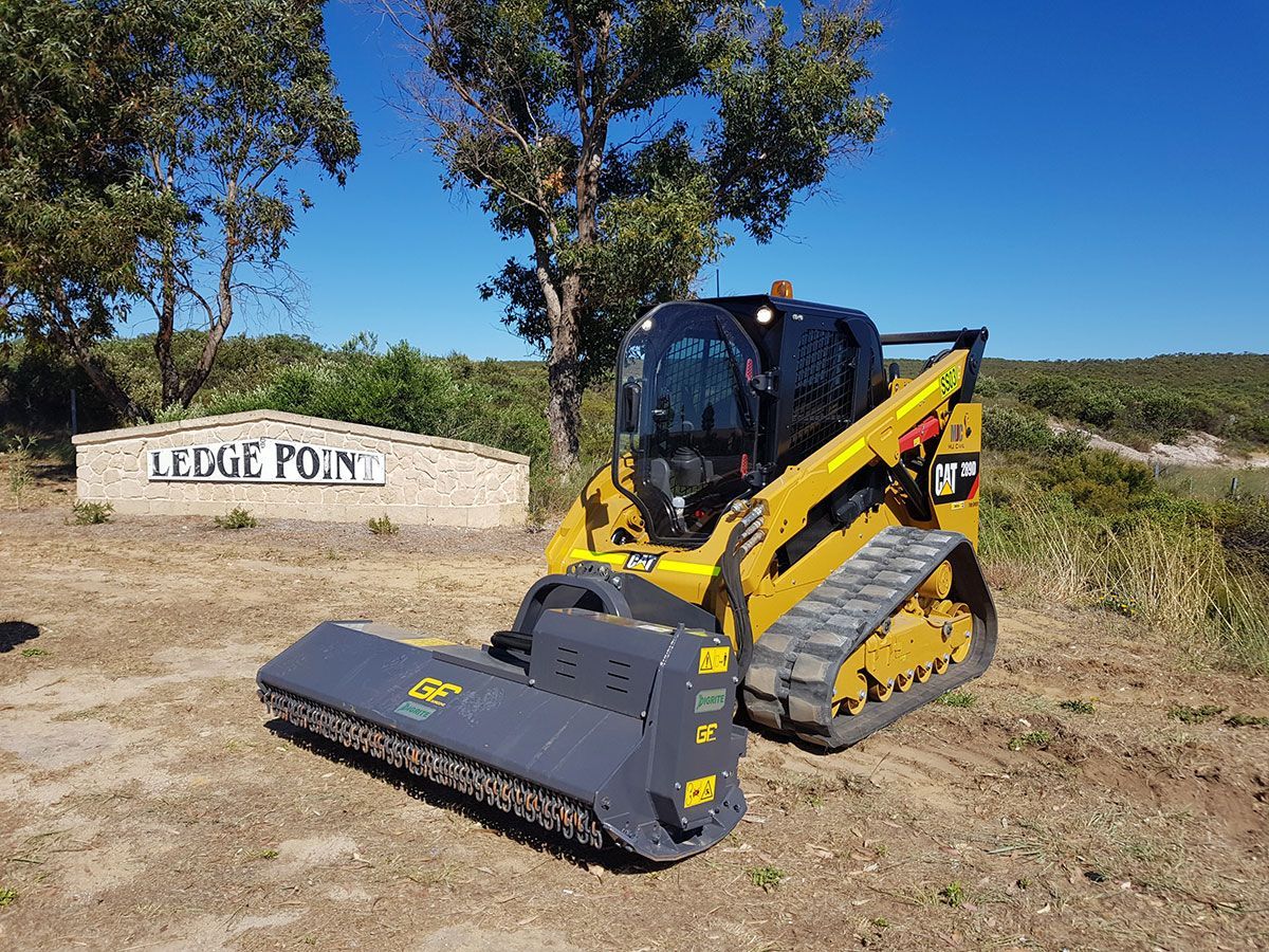 A yellow and black bulldozer is parked in a field in front of a sign.