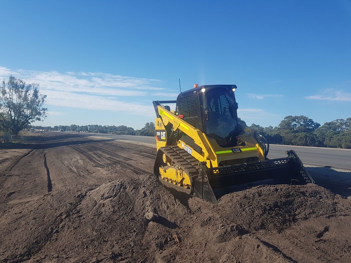 A yellow bulldozer is driving down a dirt road.