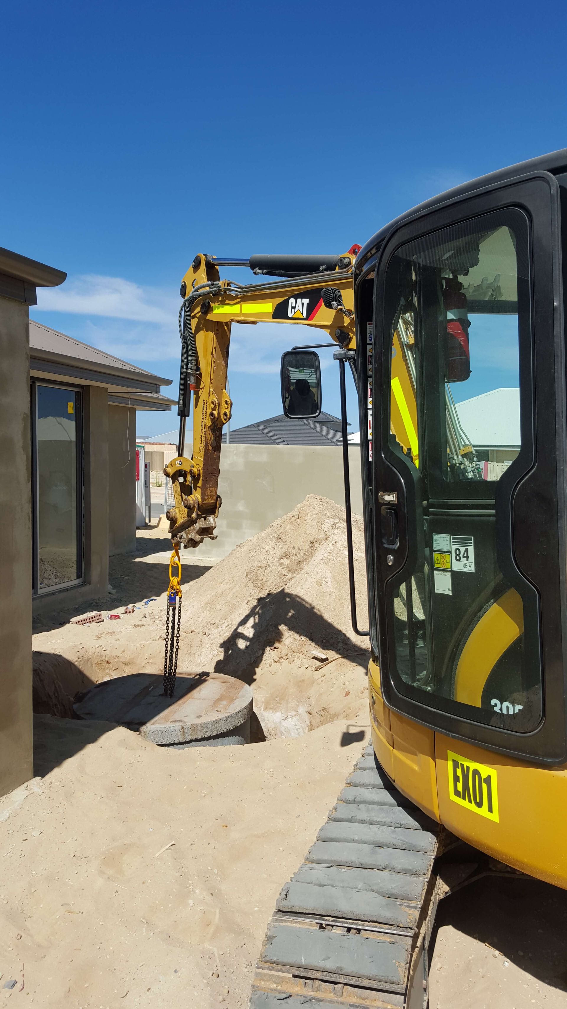 A yellow and black excavator is digging a hole in the ground.