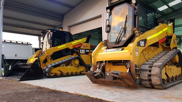 Two bulldozers are parked next to each other in a garage.