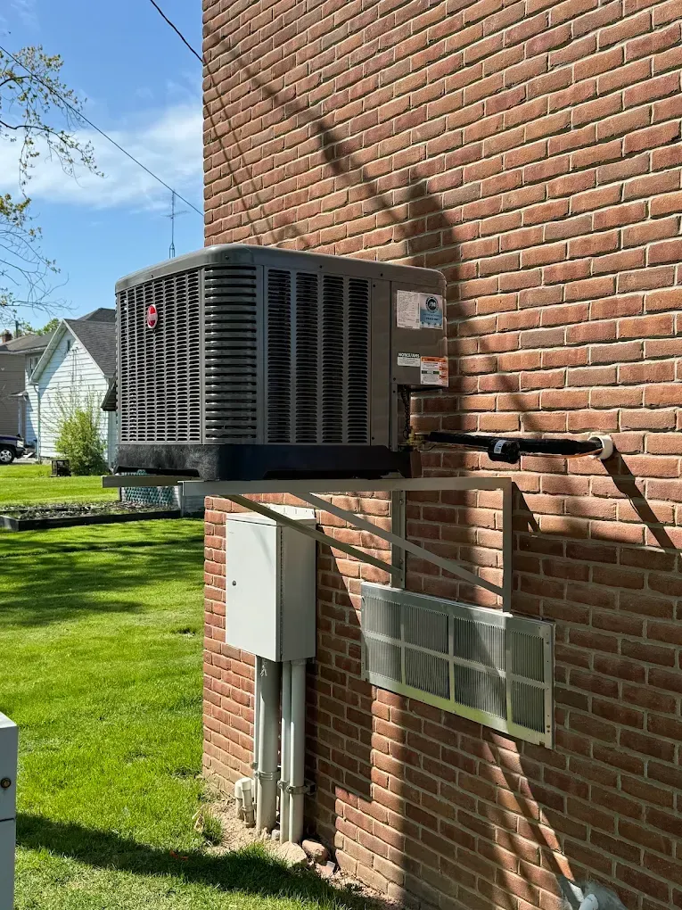 Central air conditioning unit mounted on brick building exterior.