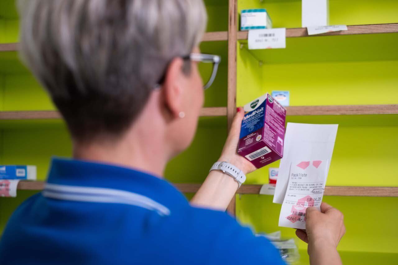 Eine Frau sieht sich in einer Apotheke eine Schachtel Pillen an.