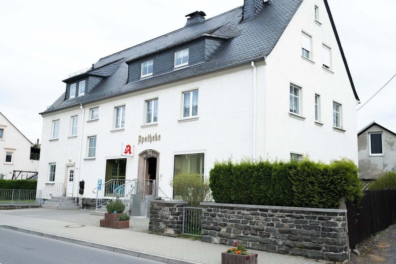 Ein großes weißes Gebäude mit einem schwarzen Dach steht am Straßenrand.