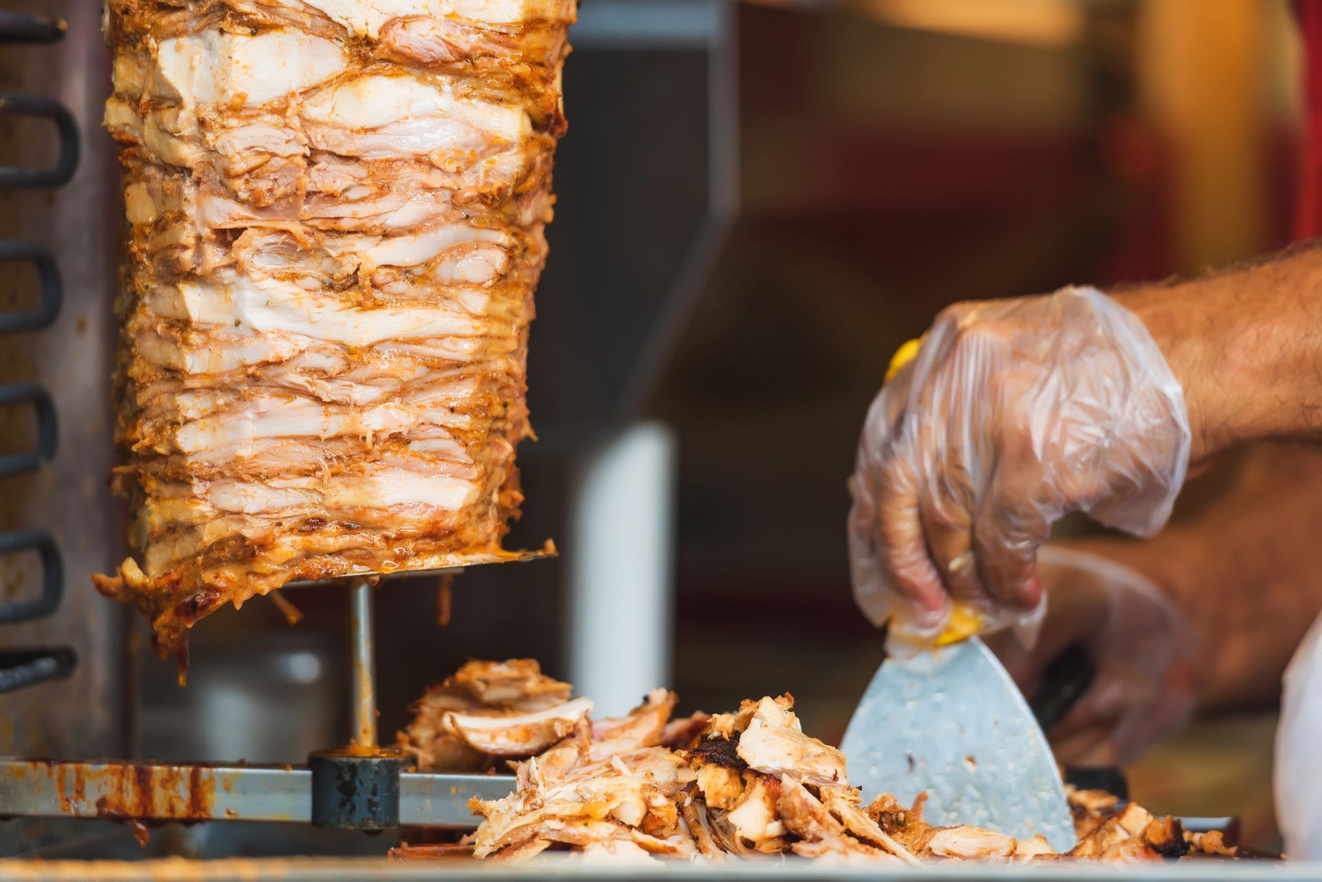 Un venditore ambulante affetta la carne da uno spiedo verticale su un bancone.