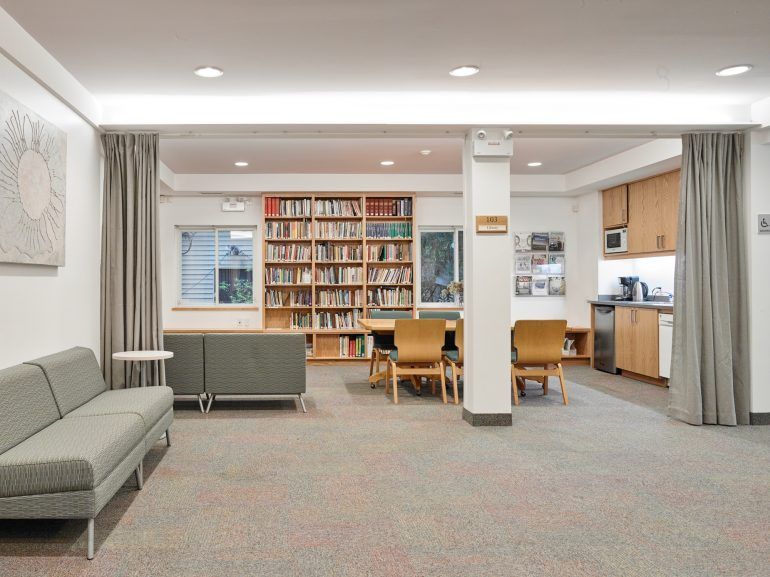 A living room with a couch , chairs , and a bookshelf.