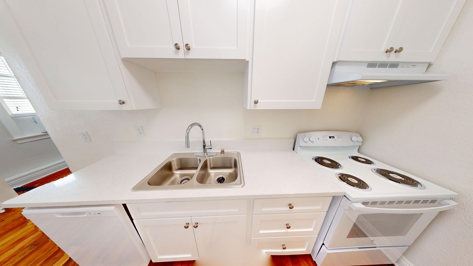White kitchen with cabinets, sink, and stove.