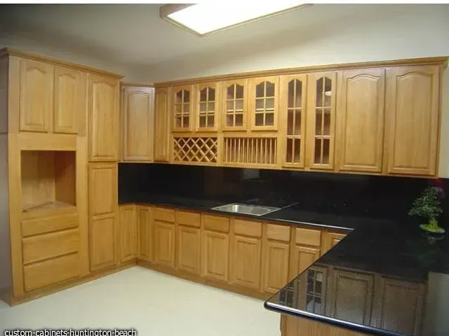 Light wood kitchen cabinets with black countertops.