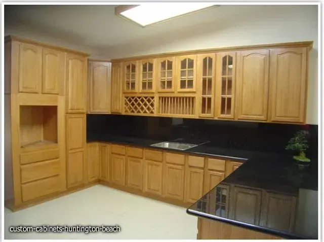 Light wood kitchen cabinets with black countertops and built-in appliances.