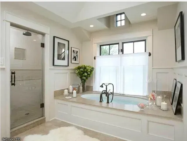 Elegant bathroom with a built-in tub, glass shower, and framed art; white walls, neutral tones.