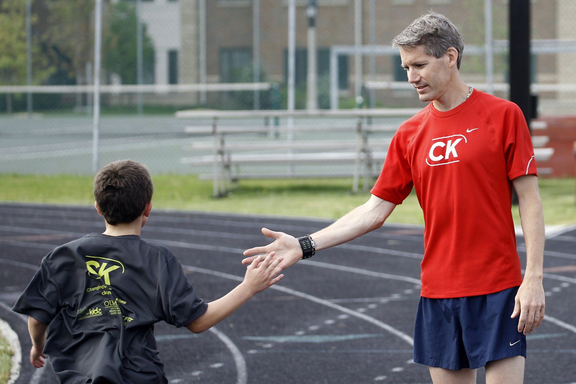 A man in a ck shirt shakes hands with another man