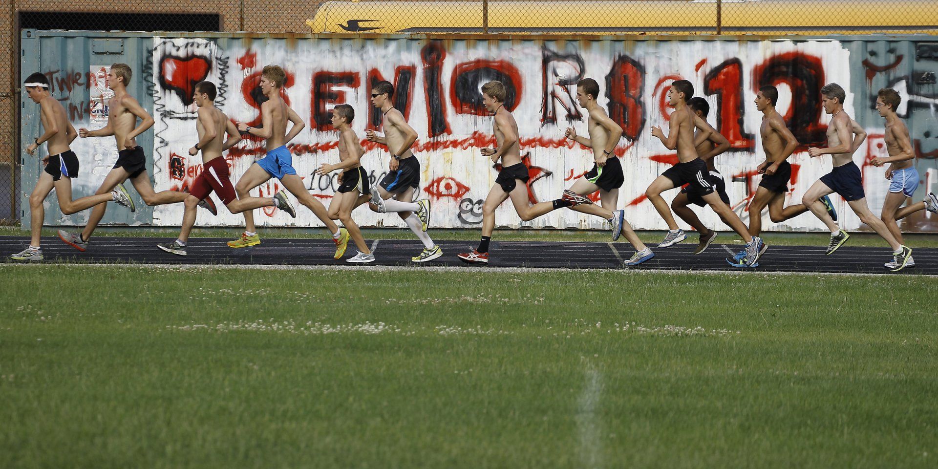 A group of runners are running in front of a wall that says seniors