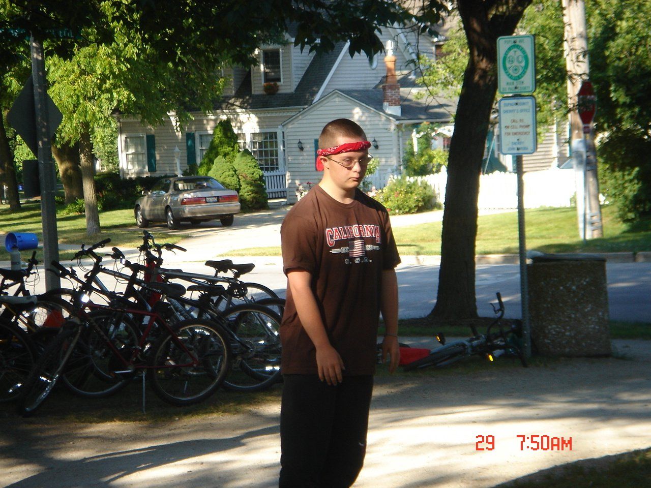 A man wearing a red headband stands on the sidewalk at 7:50 am