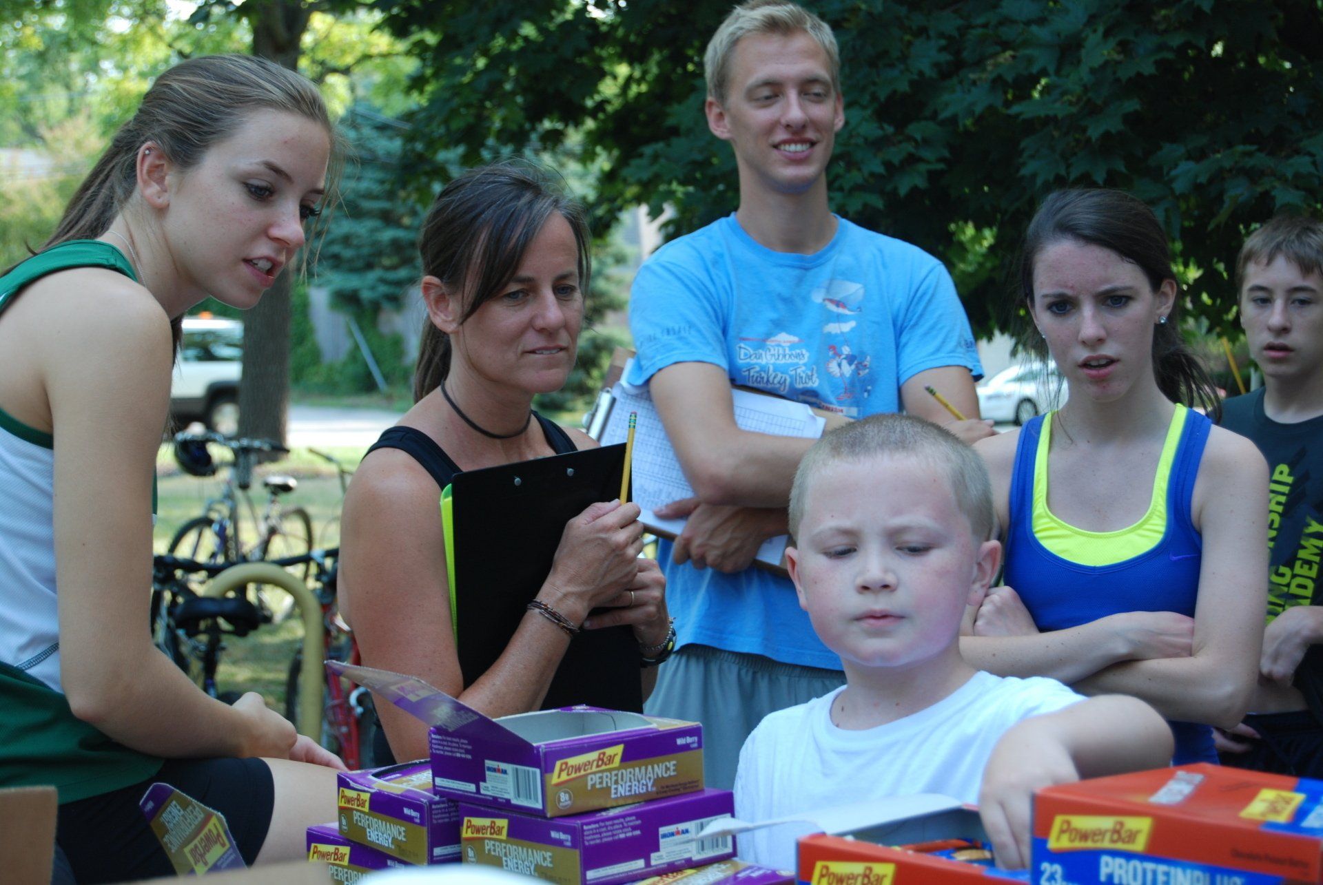 A group of people standing around a table with boxes of protein bars