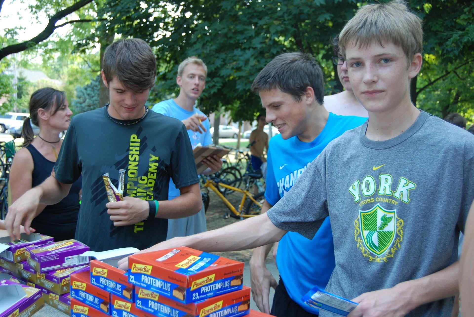 A boy wearing a york shirt is standing in front of a table full of boxes