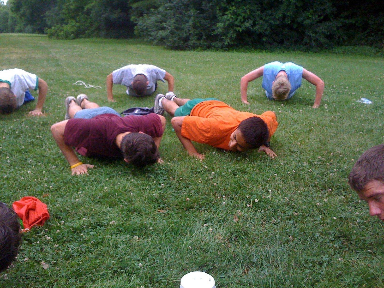 A group of kids are doing push ups in the grass