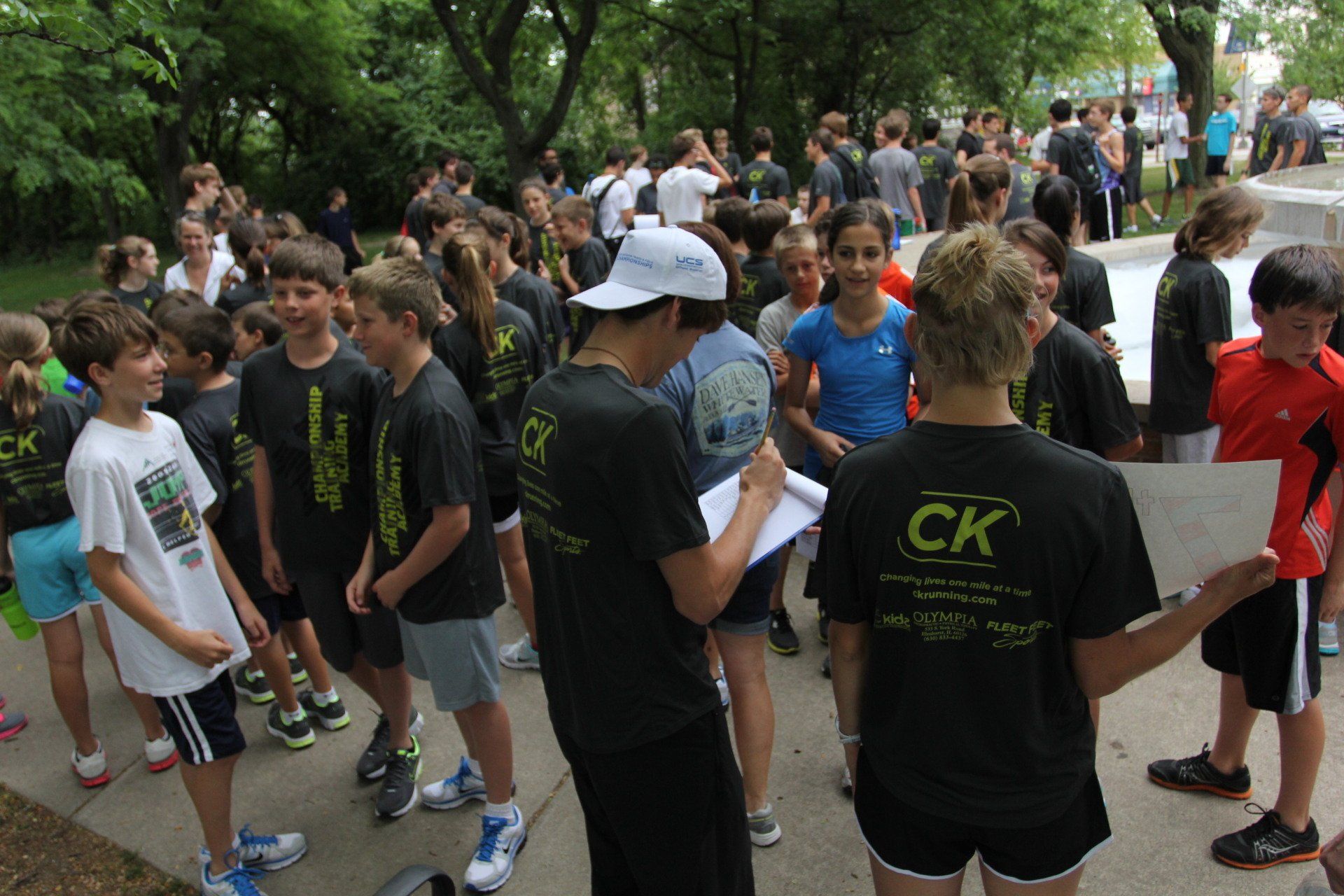 A group of children are gathered in a park wearing shirts that say ck