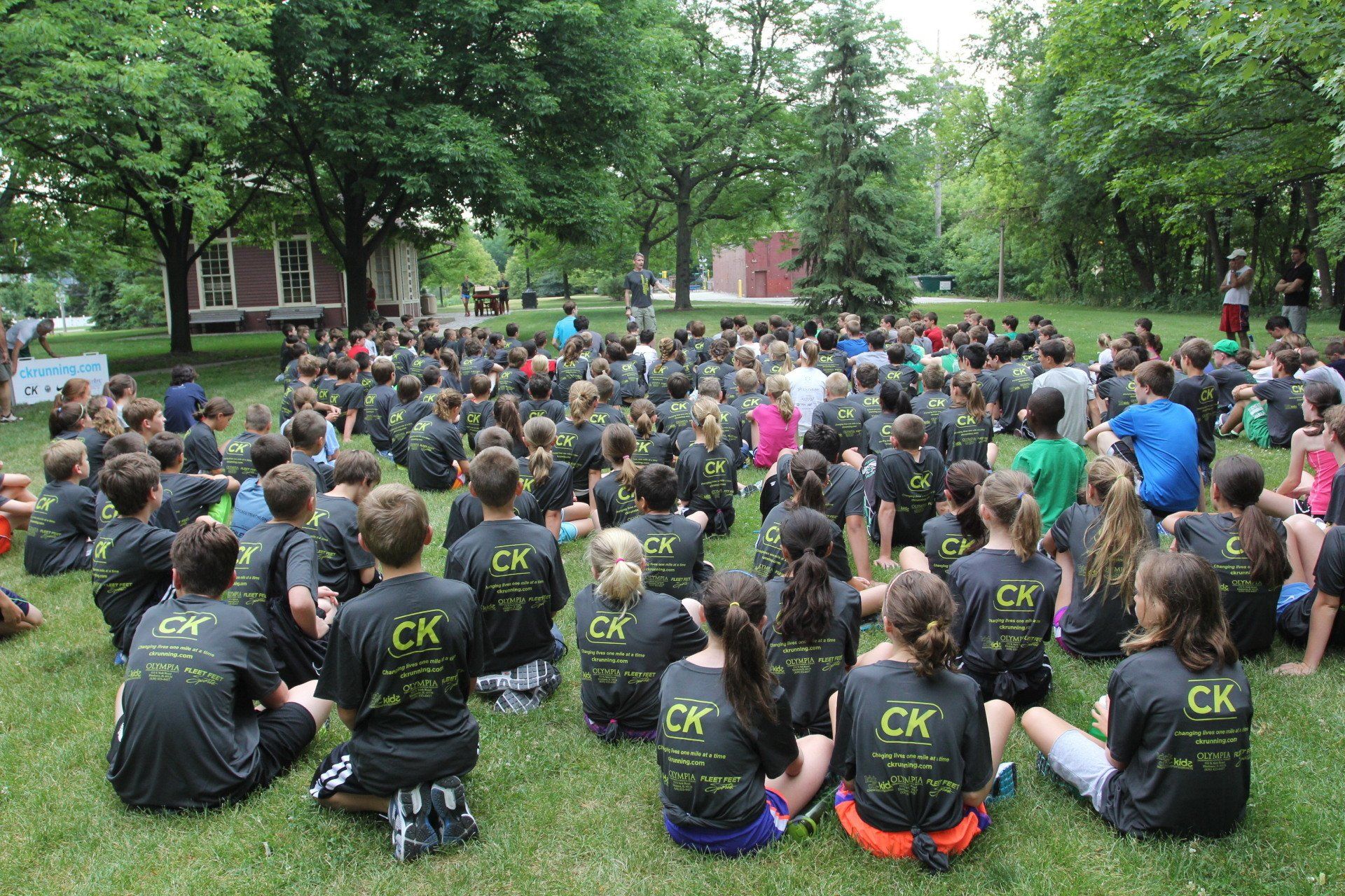 A large group of children wearing ck shirts are sitting in the grass
