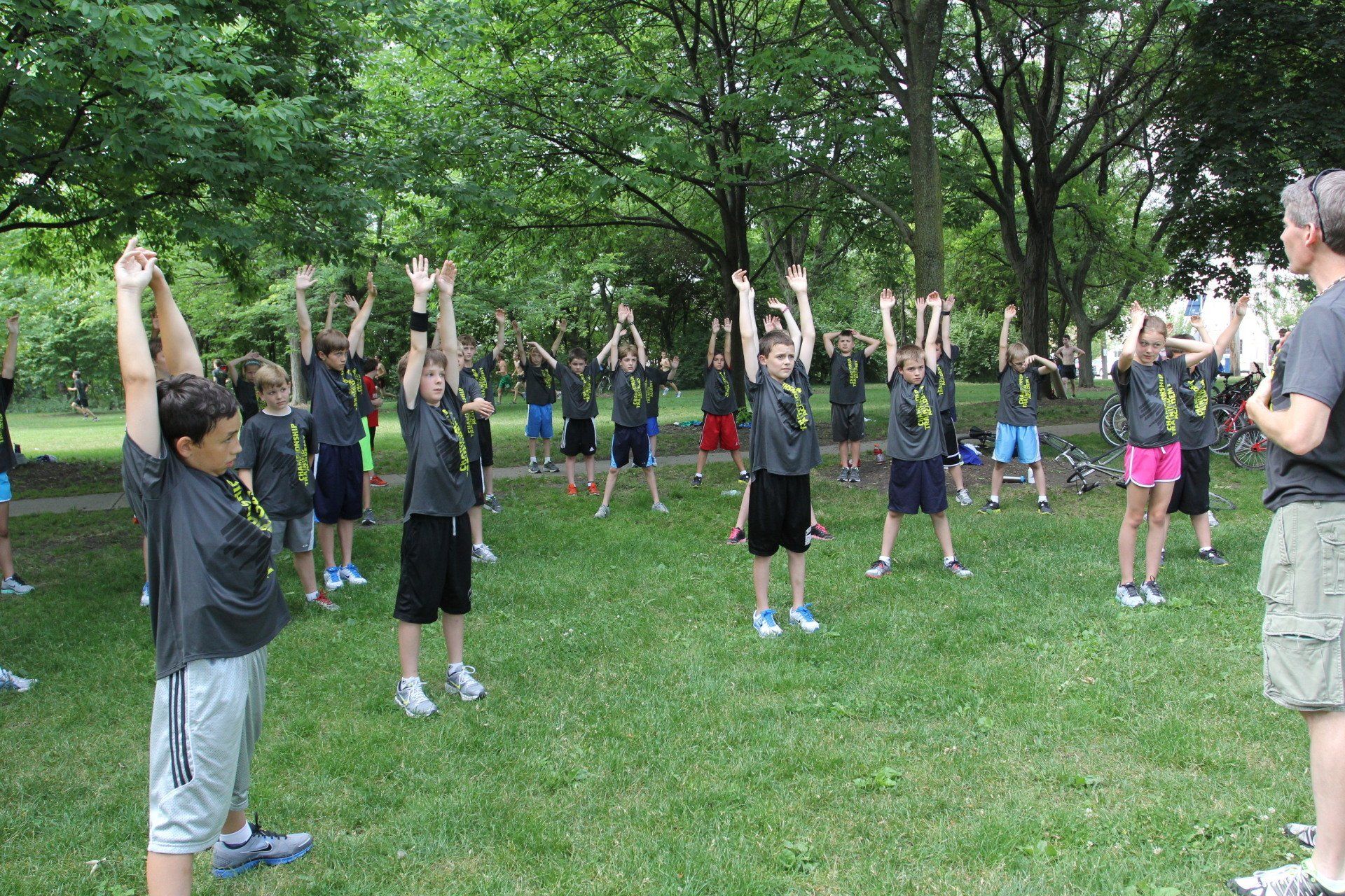 A group of children are doing stretching exercises in a park.