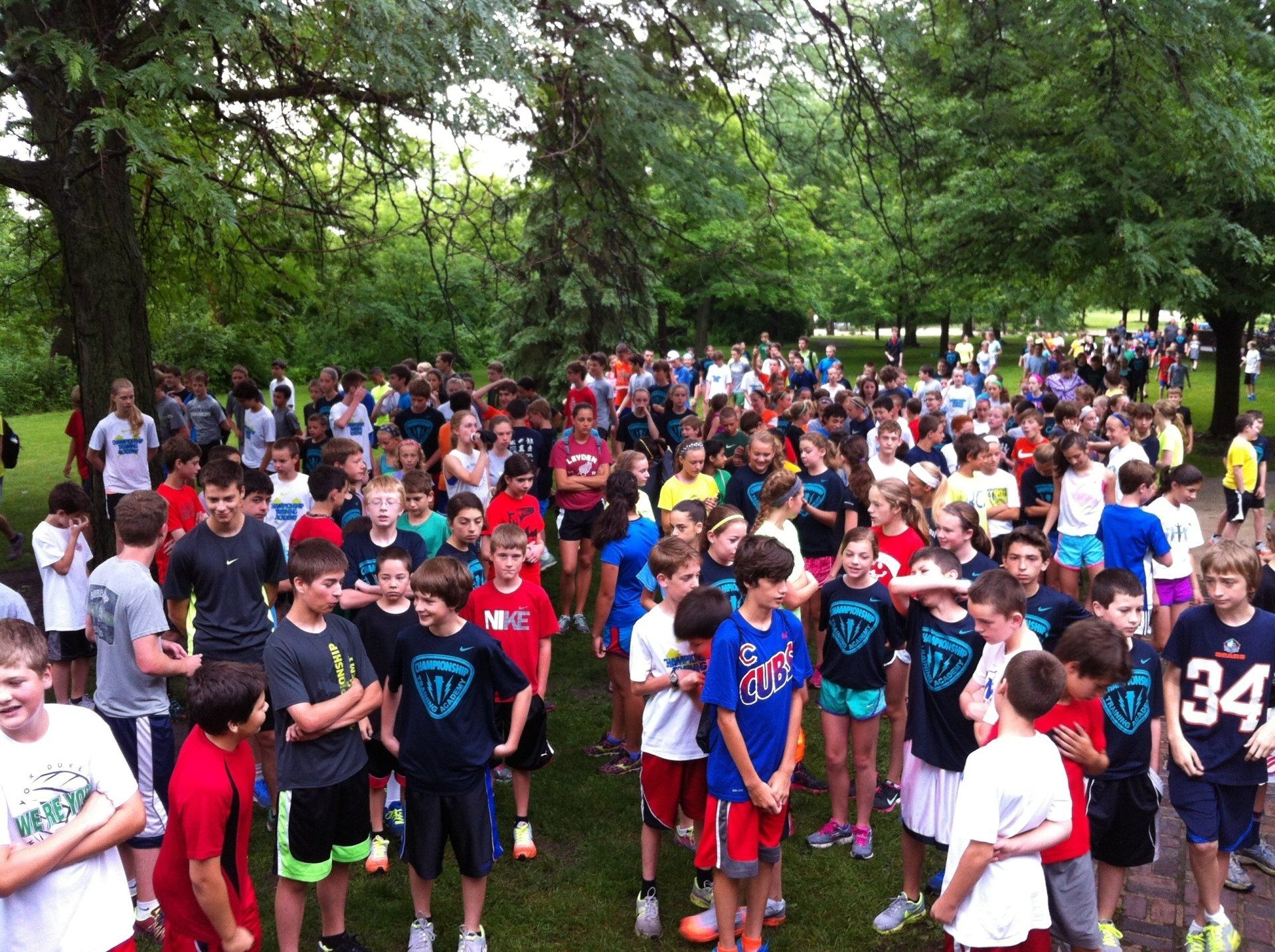 A large group of children are gathered in a park wearing shirts with the number 34 on them