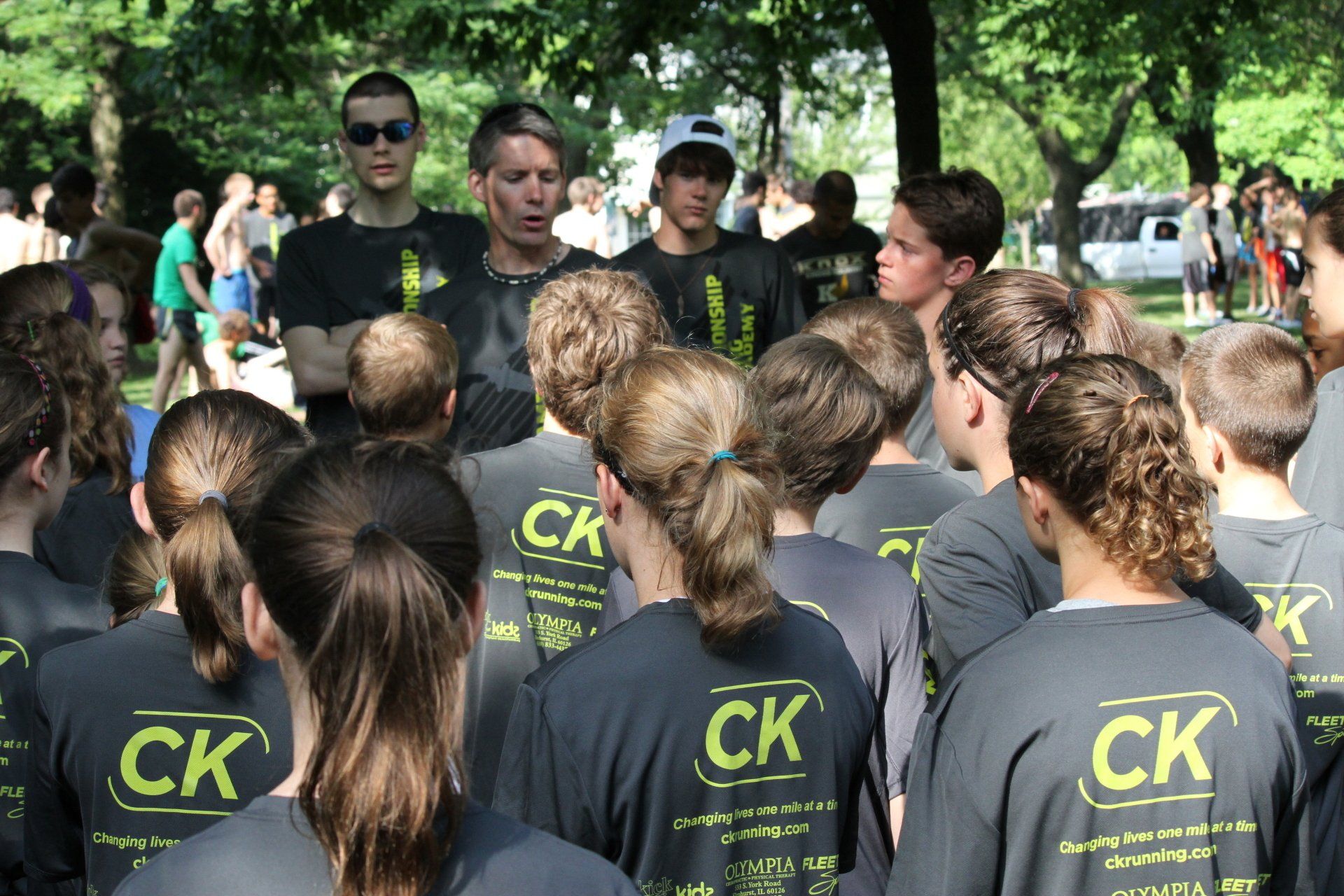 A group of people wearing ck shirts stand in a park