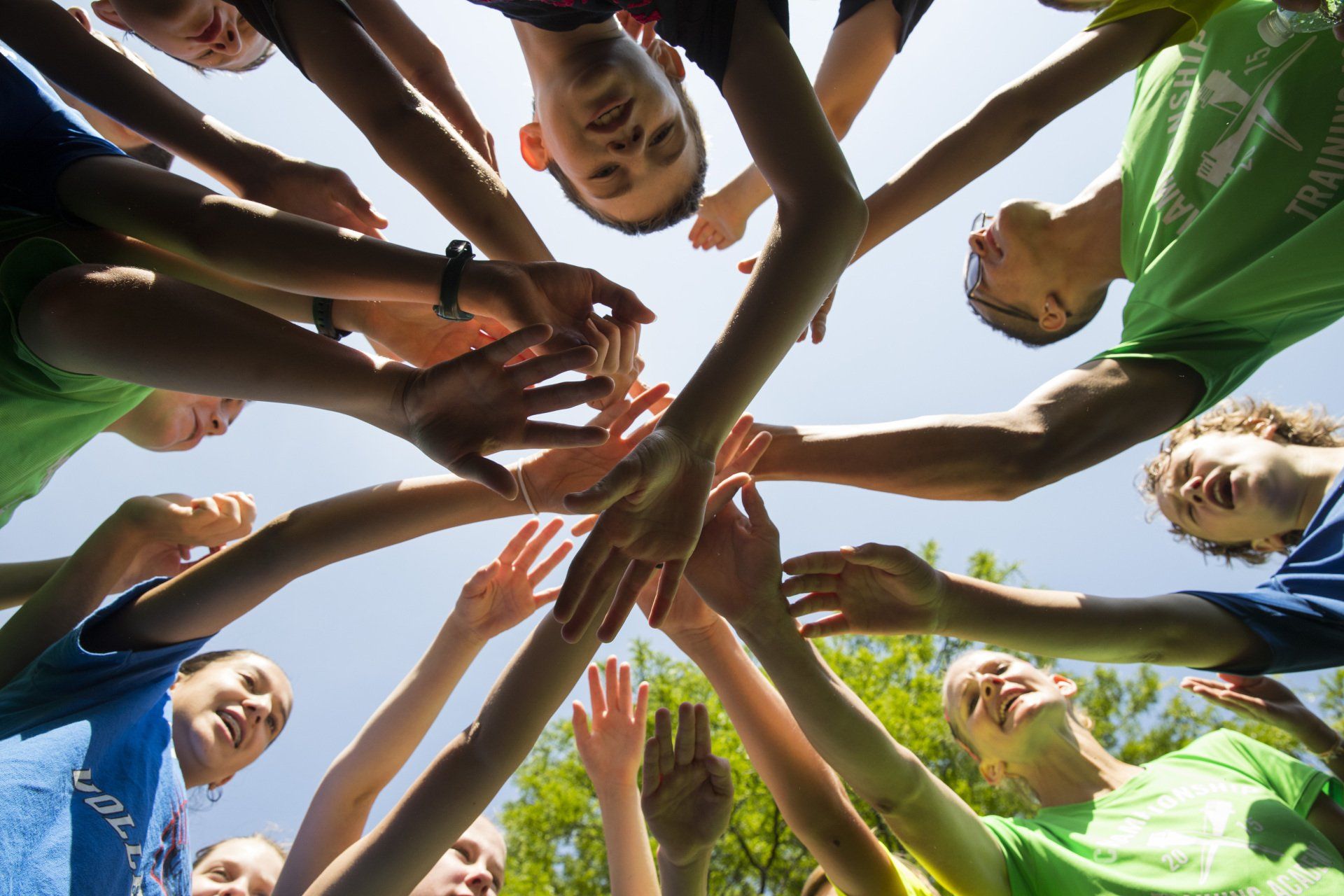 A group of people are putting their hands together in a circle.