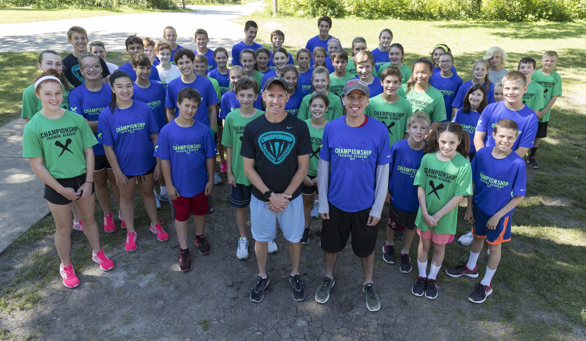 A large group of people wearing blue and green shirts are posing for a picture.