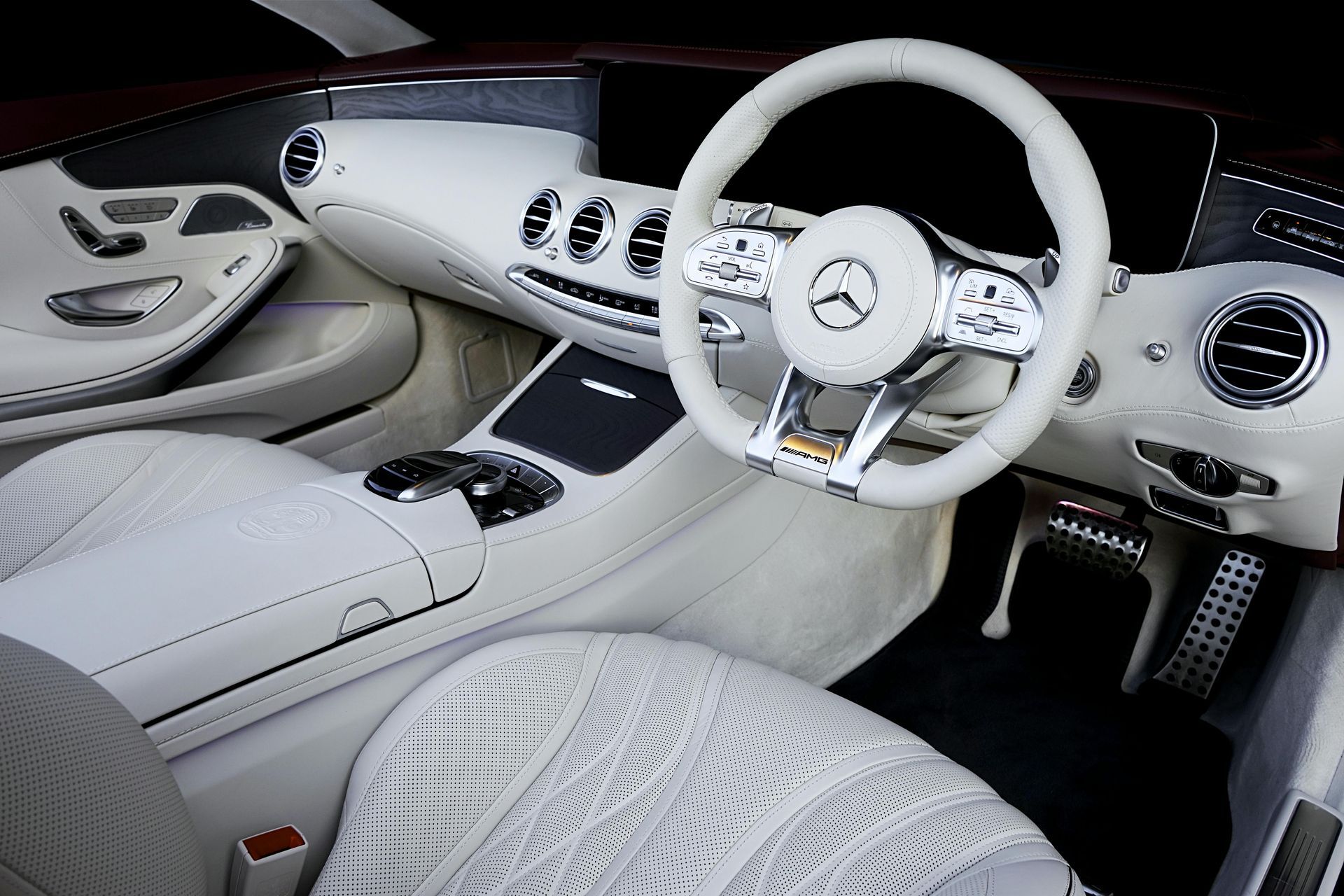 Cream-colored interior of a Mercedes-Benz with white steering wheel and seats.