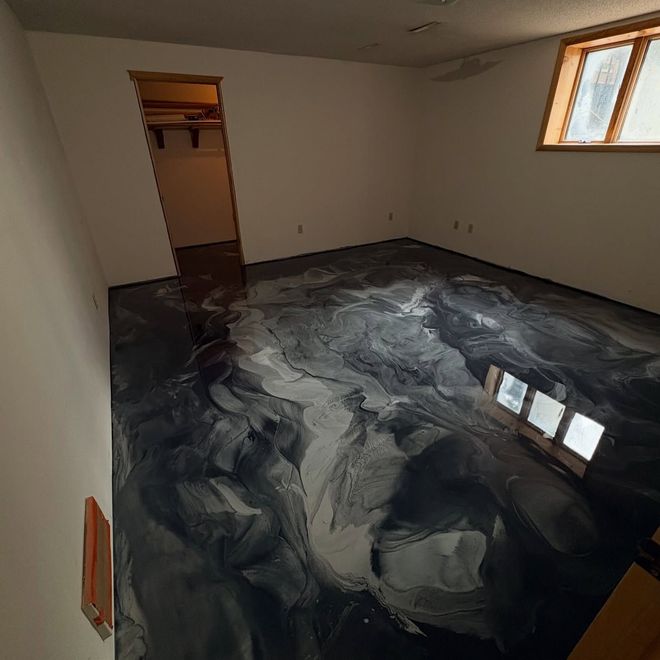 Empty room with glossy black-and-white marbled floor and a small window on the right.