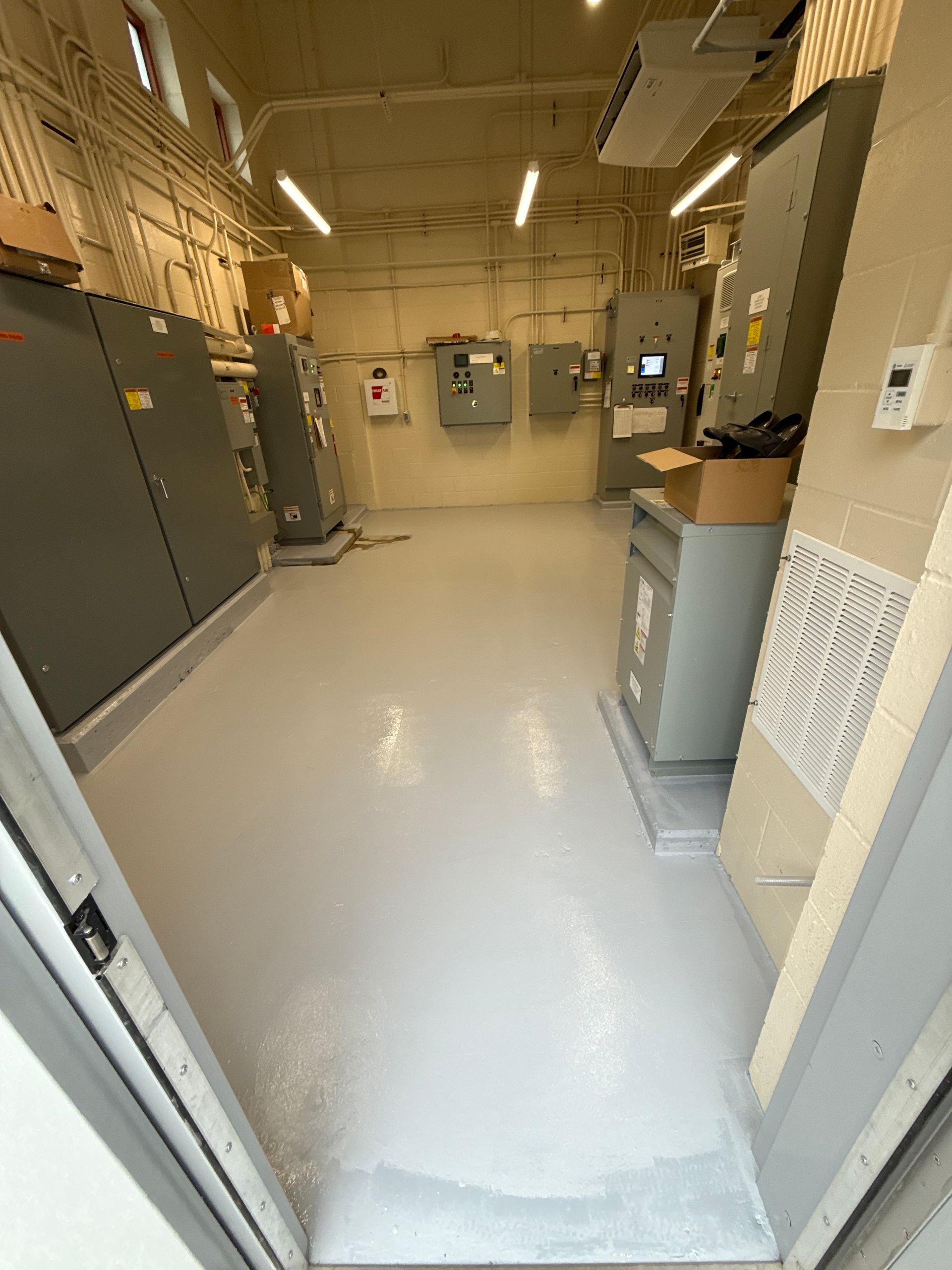 Empty industrial utility room with gray cabinets, pipes, and a light-colored floor