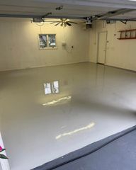 Empty garage with glossy white floor, beige walls, and a small window.