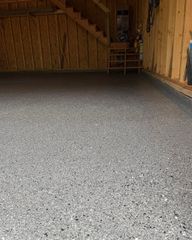 Empty unfinished garage with exposed wooden framing and a gray speckled floor