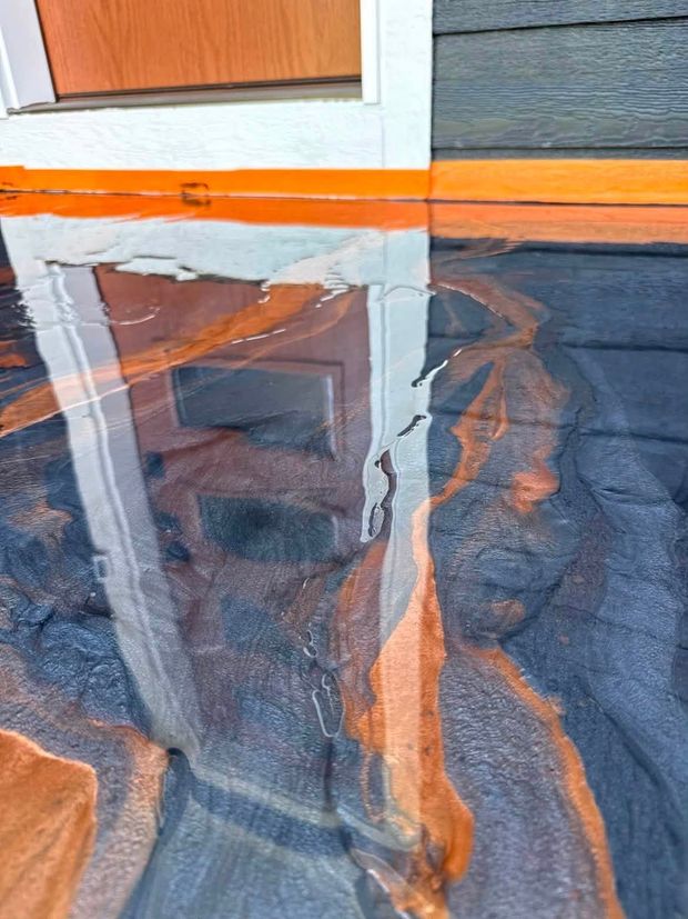 Reflections of a house and orange trim in a wet blue surface