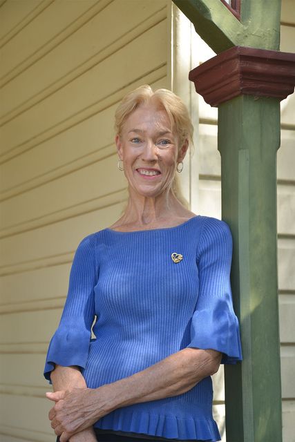 Smiling lady standing in front of brick wall with window and door