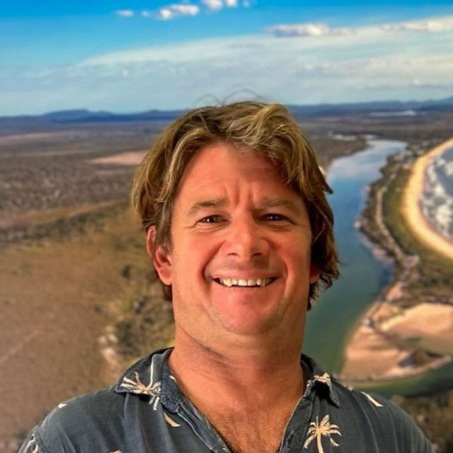 Bust image of smiling man standing in front of scene image