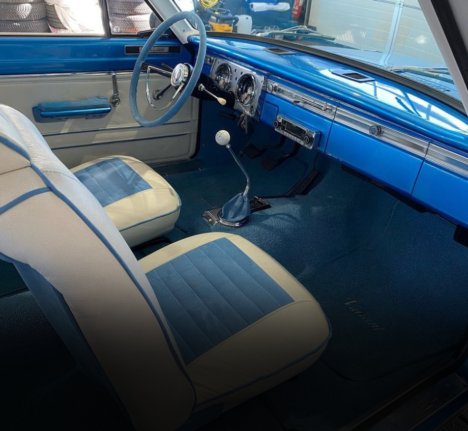 Restauration intérieur d'une voiture bleue avec des sièges blancs et un volant