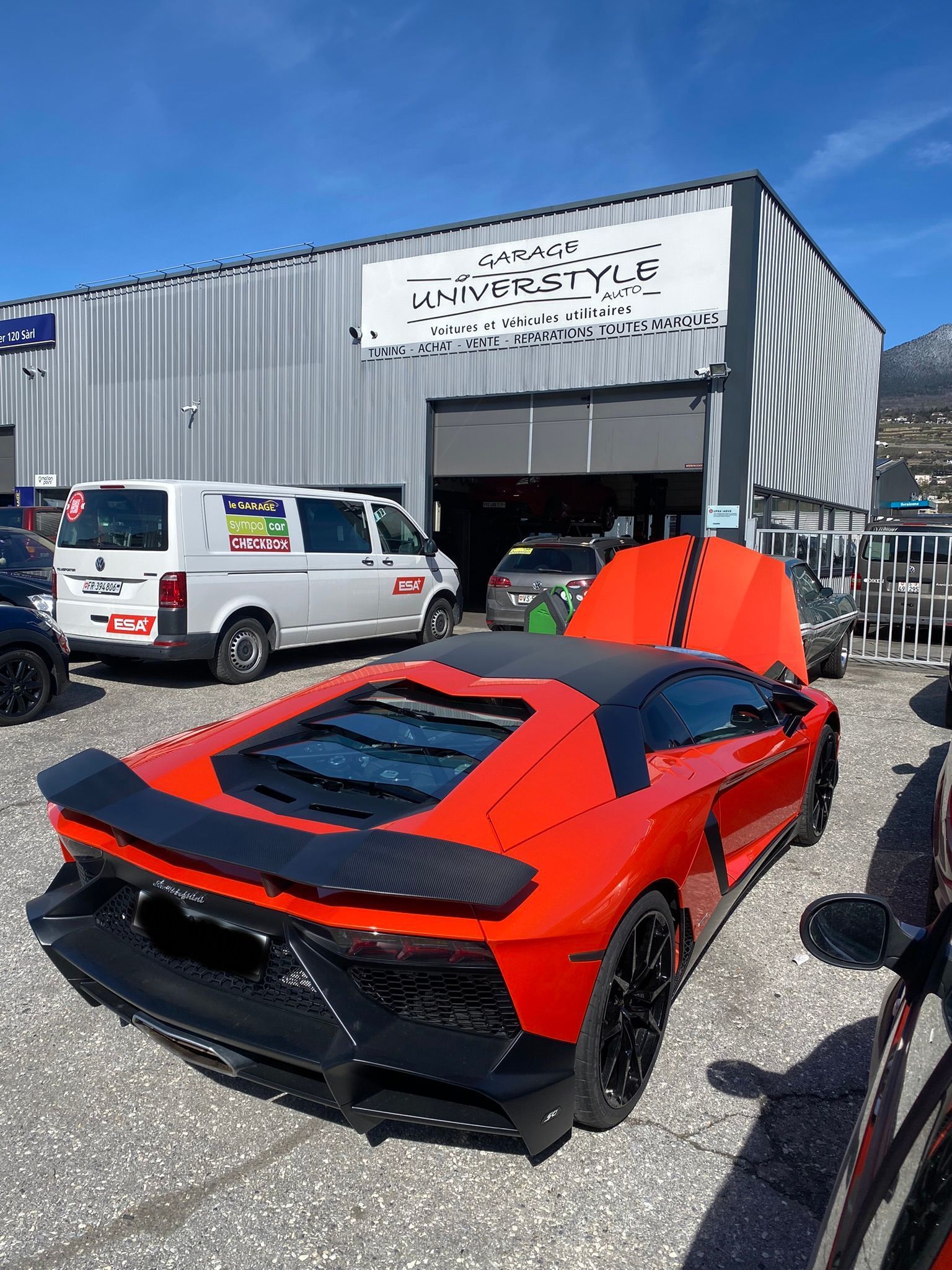 Une Lamborghini Aventador rouge est garée devant un immeuble.