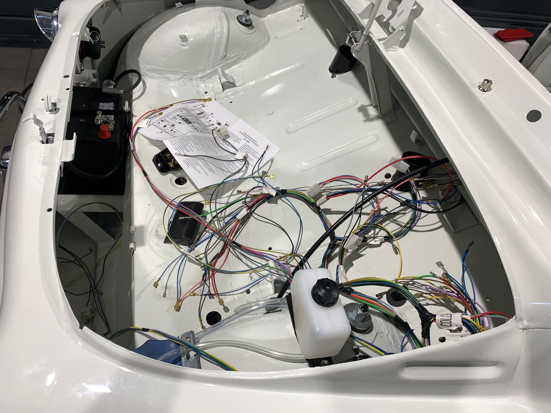 Le coffre d’une voiture blanche avec beaucoup de fils qui en sortent.